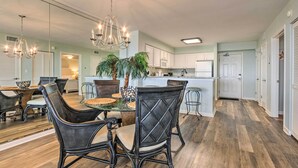 A dining area with a glass-top table, wicker chairs, and a chandelier.