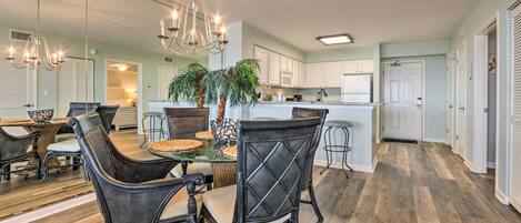 A dining area with a glass-top table, wicker chairs, and a chandelier.