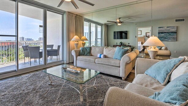 A spacious living room with a large glass coffee table, two sofas, and a ceiling fan.