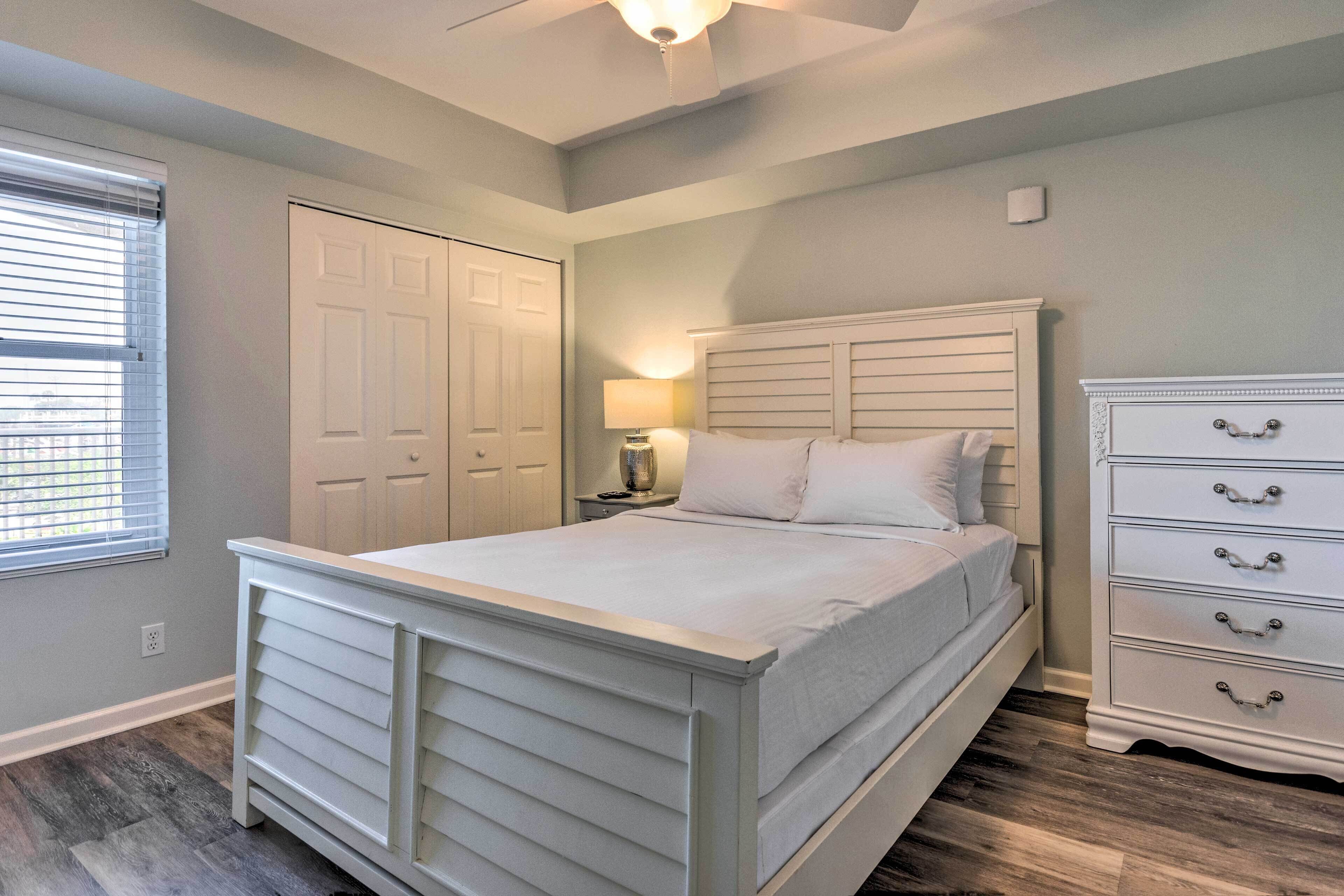 A bedroom with a bed, a dresser, a nightstand, a lamp, and a closet.