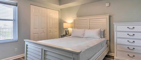 A bedroom with a bed, a dresser, a nightstand, a lamp, and a closet.