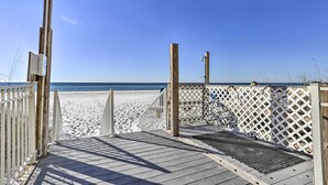 A wooden boardwalk leading to a sandy beach with a clear blue sky.