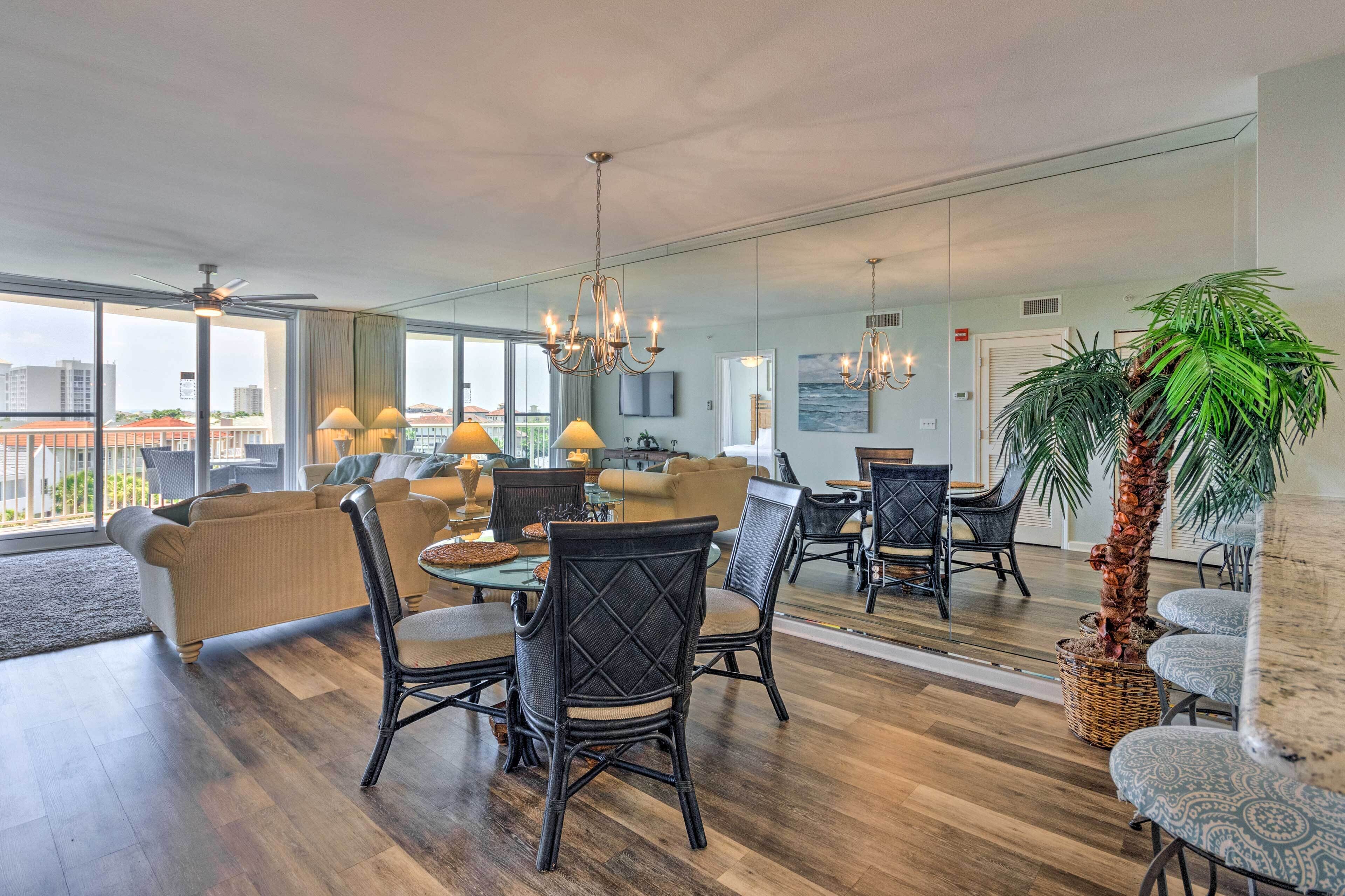A spacious living area with a dining table, chairs, and a large potted plant.