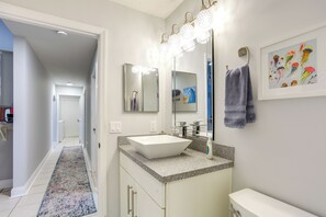 A bathroom with a white sink, a large mirror, and a lighted vanity.