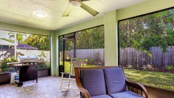 Enjoy al fresco dining and relaxation in this outdoor space with a grill, ceiling fan, and comfortable seating.