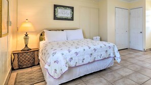 A bedroom with a bed, a bedside lamp, a framed sign on the wall, and a door. - Beachfront Cottage in St Augustine - Pet Friendly! (St. Augustine)