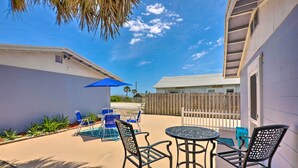 A patio with a pool table, chairs, and a blue umbrella. - Beachfront Cottage in St Augustine - Pet Friendly! (St. Augustine)