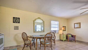 A dining area with a table and chairs, a mirror, a small cabinet, and a chair with a cushion. - Beachfront Cottage in St Augustine - Pet Friendly! (St. Augustine)