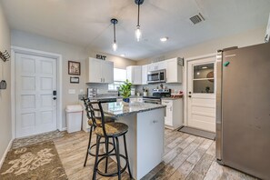 A modern kitchen with white cabinets, a stainless steel refrigerator, and a central island with bar stools.