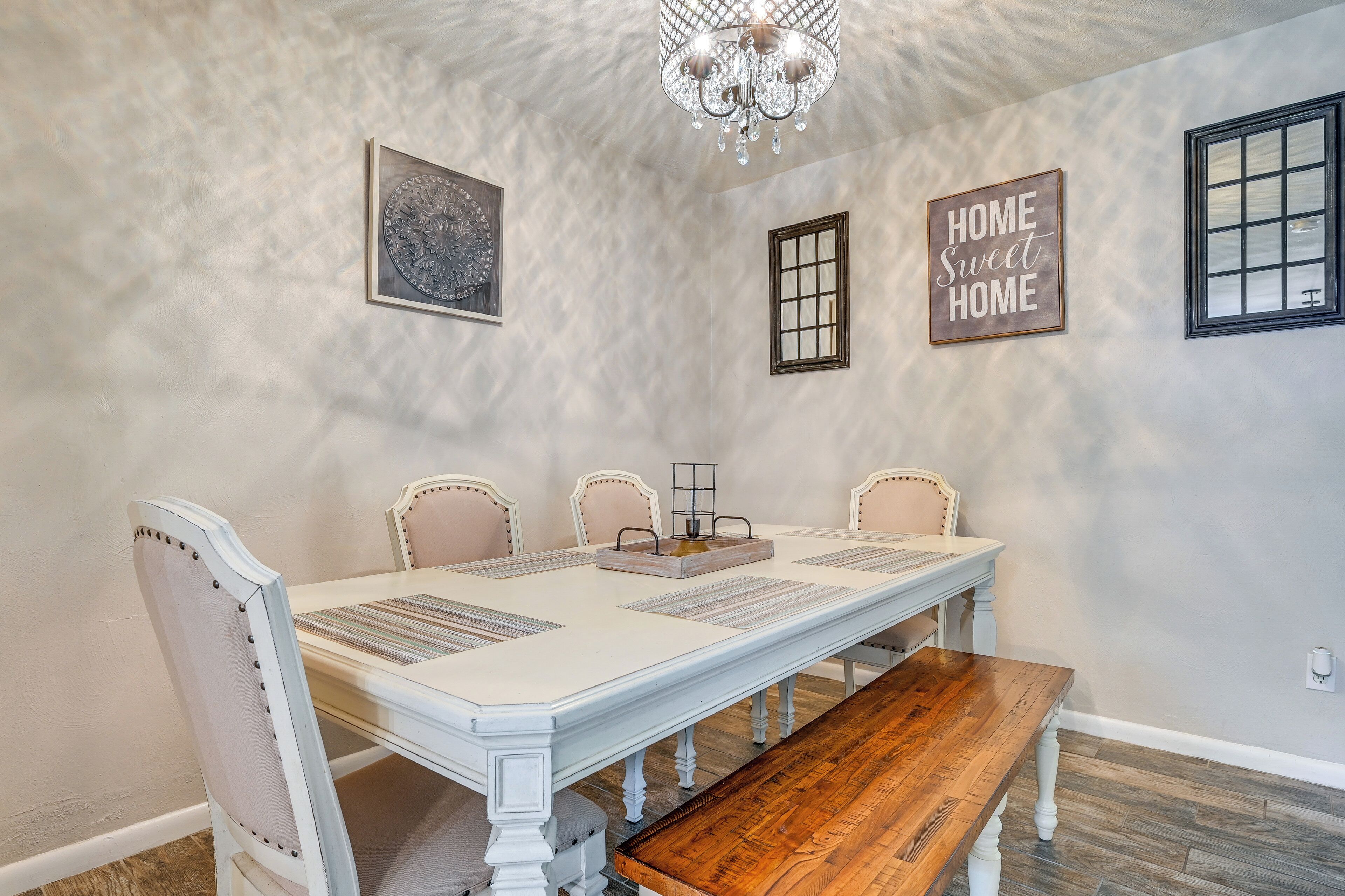 Un espace repas comprenant une table blanche, un banc en bois et quatre chaises.