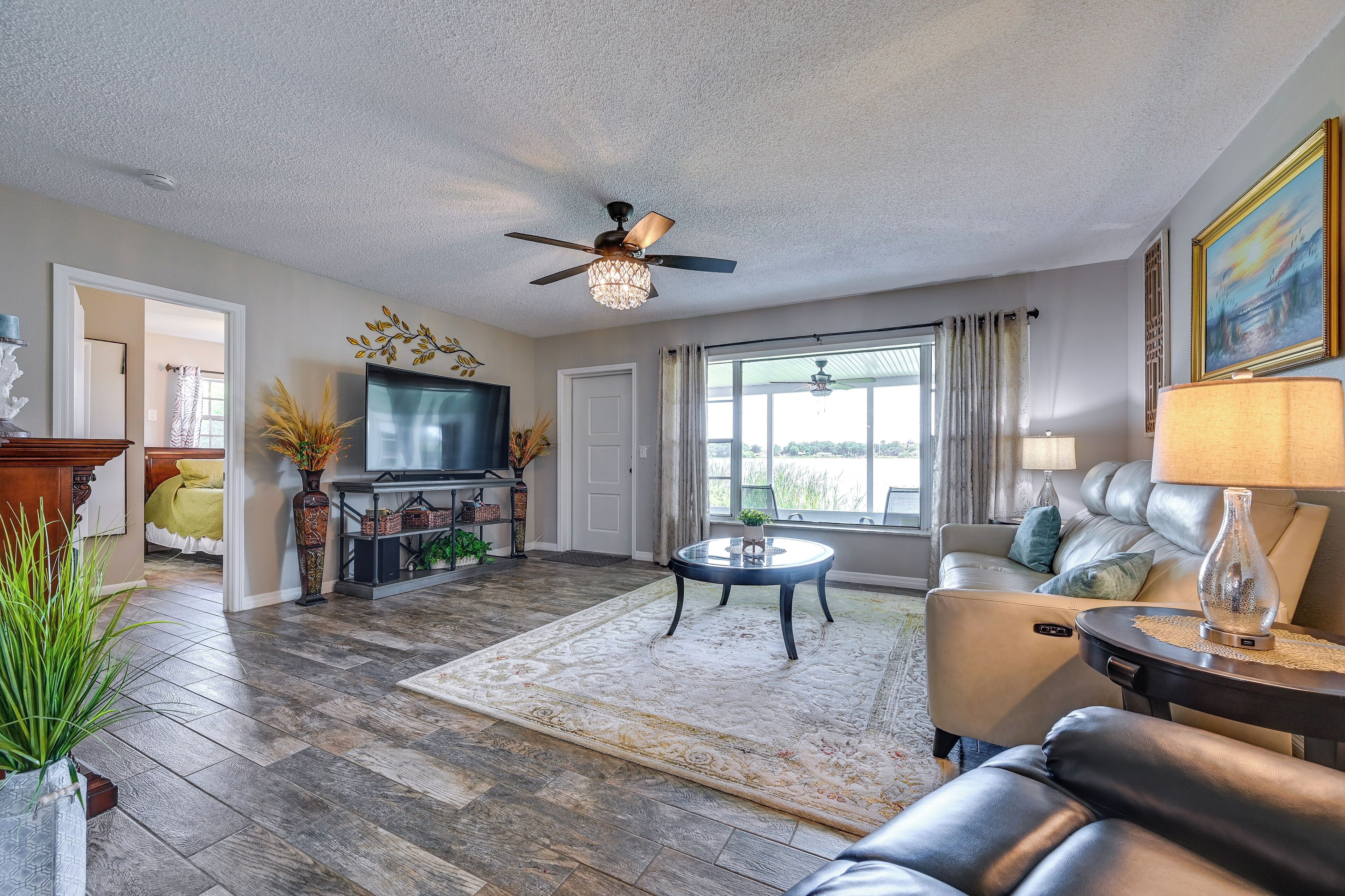A living room with a ceiling fan, a television, a sofa, a coffee table, and a large window.
