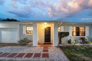 A two-story house with a front porch, a garage, and a well-maintained lawn. - Hook, Line & Leisure: Lakefront Gem w/ Porch! (Winter Haven)