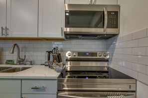 Cozinha com armários brancos, micro-ondas de aço inoxidável e forno duplo.