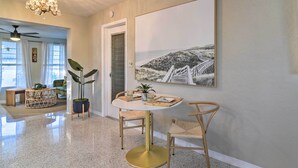 A spacious living area with a round table, two chairs, a potted plant, and a large framed picture on the wall. - Lush Seminole Surf Inn w/ Backyard Fire Pit! (Seminole)