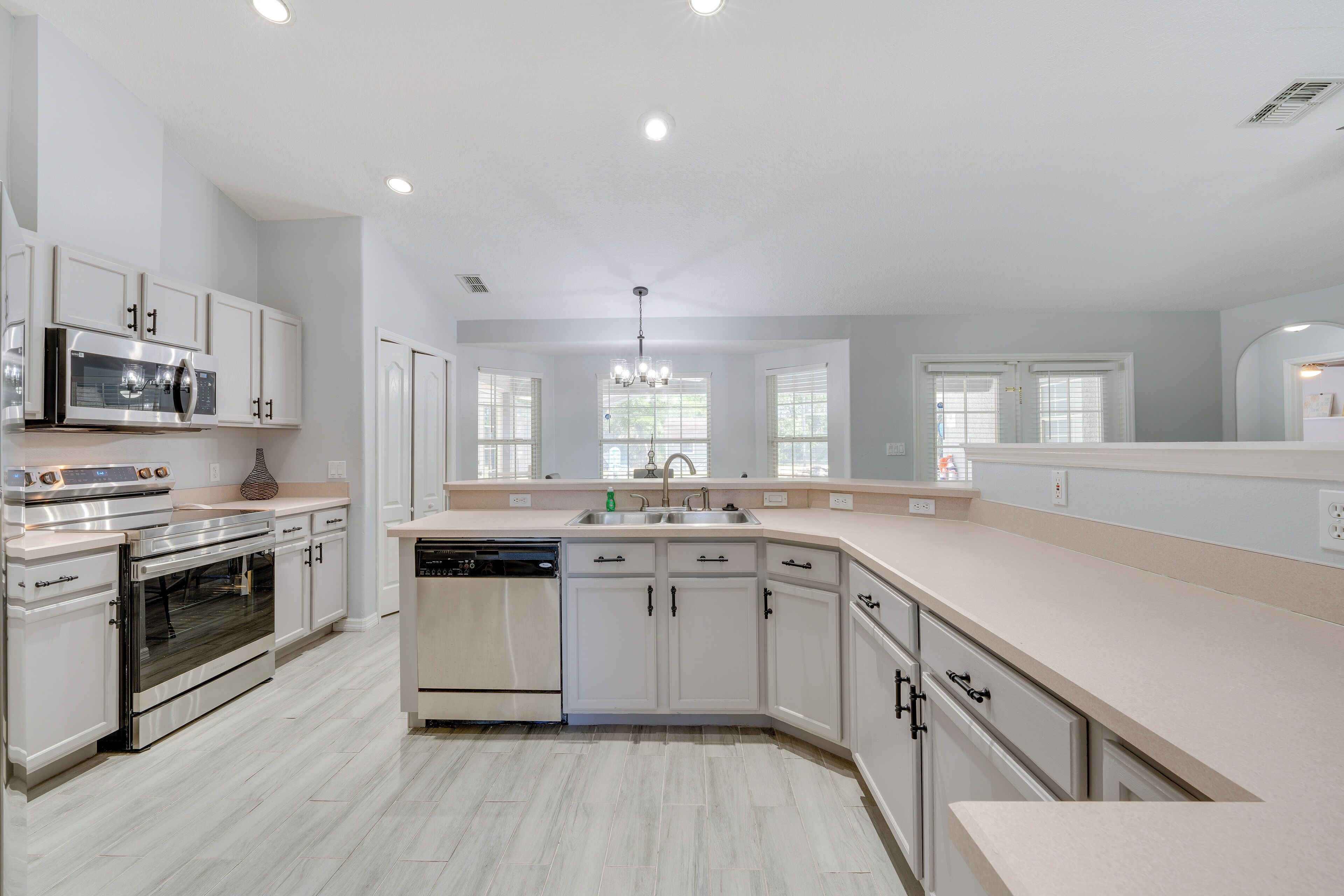 A modern kitchen with white cabinetry, stainless steel appliances, and a large island.