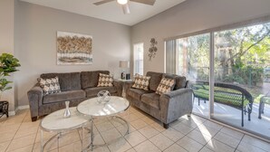 A living room with a sofa set, a glass coffee table, and a ceiling fan.