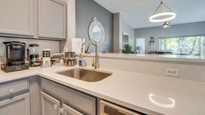 A modern kitchen with a large sink, stainless steel appliances, and a decorative mirror.