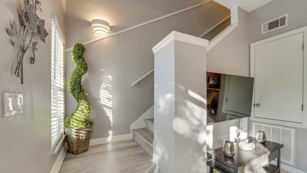 A staircase with a wooden finish, a wall-mounted light fixture, and a decorative plant.