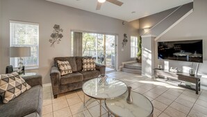 A living room with a sofa, coffee table, TV, and a ceiling fan.