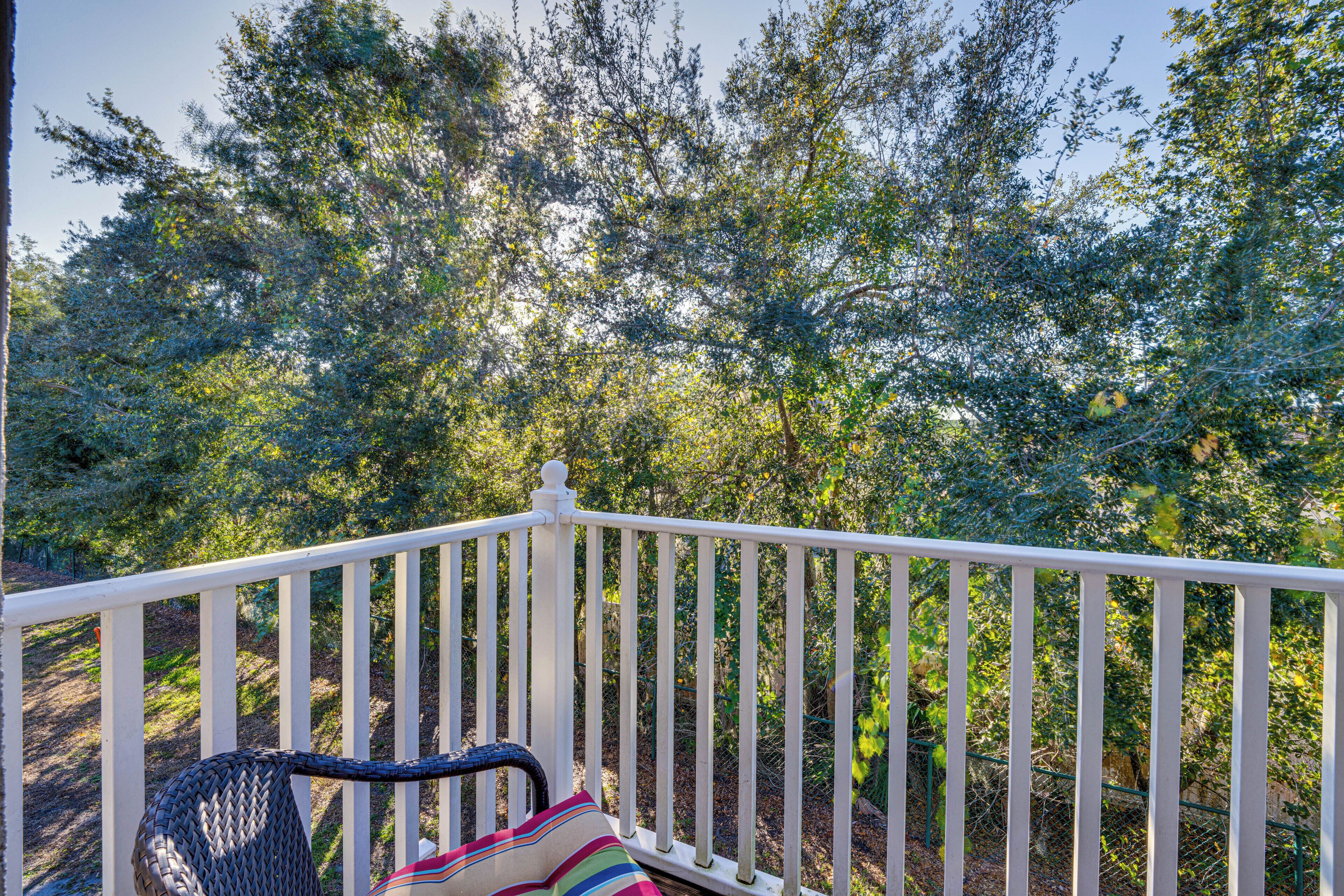 Une terrasse en bois peinte en blanc, avec une chaise en osier et un coussin à rayures.