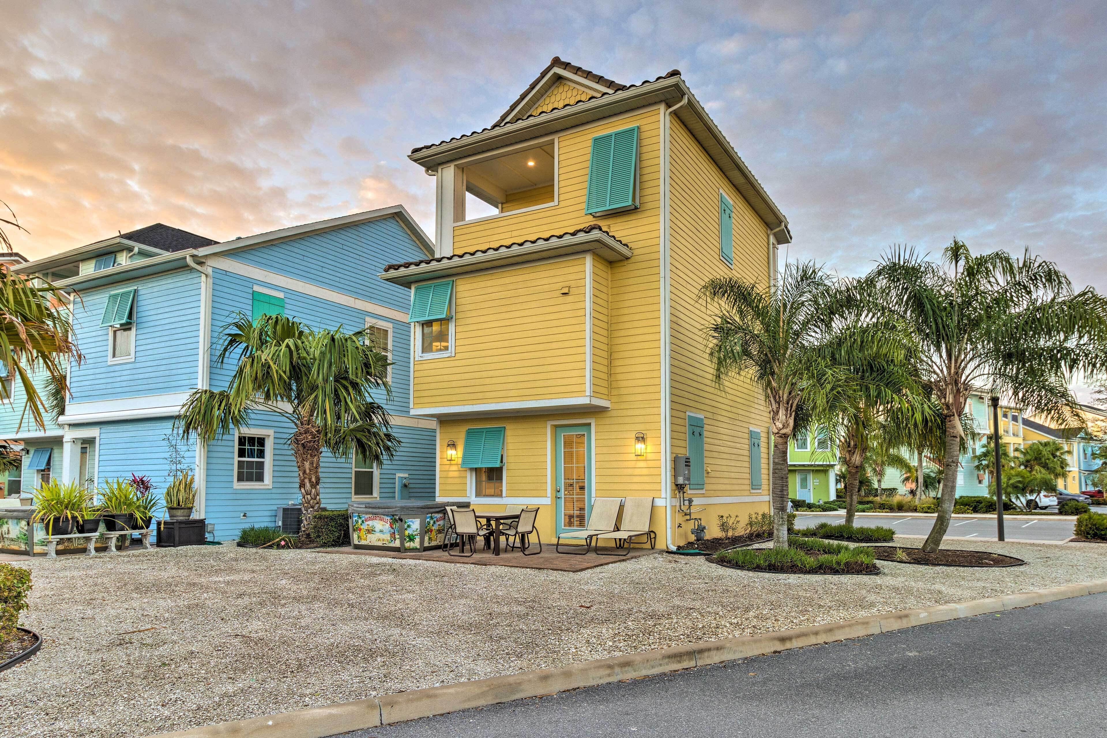 A two-story house with a balcony, a patio with outdoor furniture, and a gravel driveway.