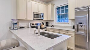 A modern kitchen with white cabinets, stainless steel appliances, a double sink, and a built-in oven. - 3 Mi to Disney: Home w/ Hot Tub in Margaritaville! (Kissimmee)