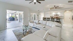A spacious living room with a large sectional sofa, a glass coffee table, and a ceiling fan. - Luxe Waterfront Oasis w/ Dock, Heated Pool & Spa! (Port Charlotte)