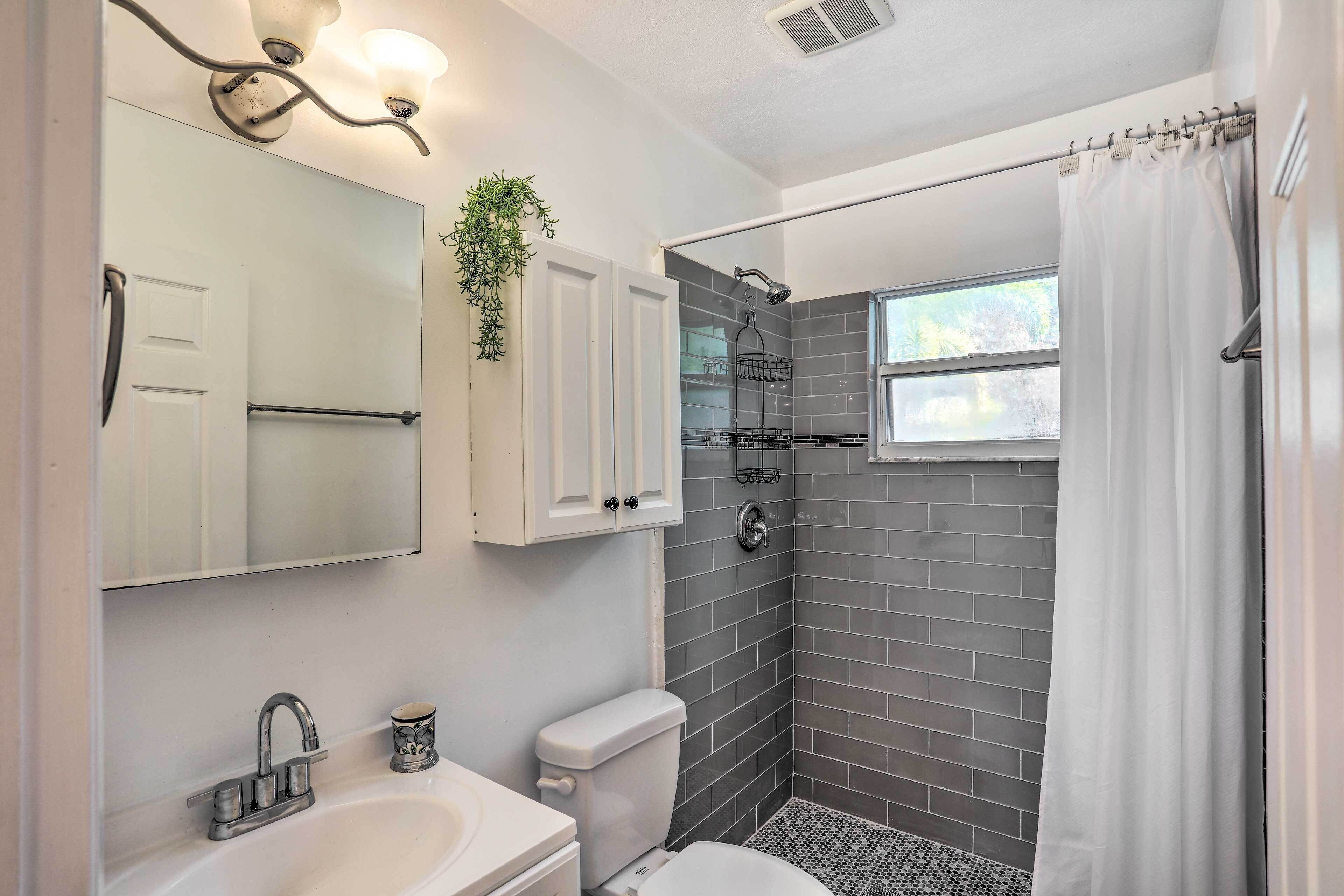 A modern bathroom with a shower, toilet, sink, and a mirror.