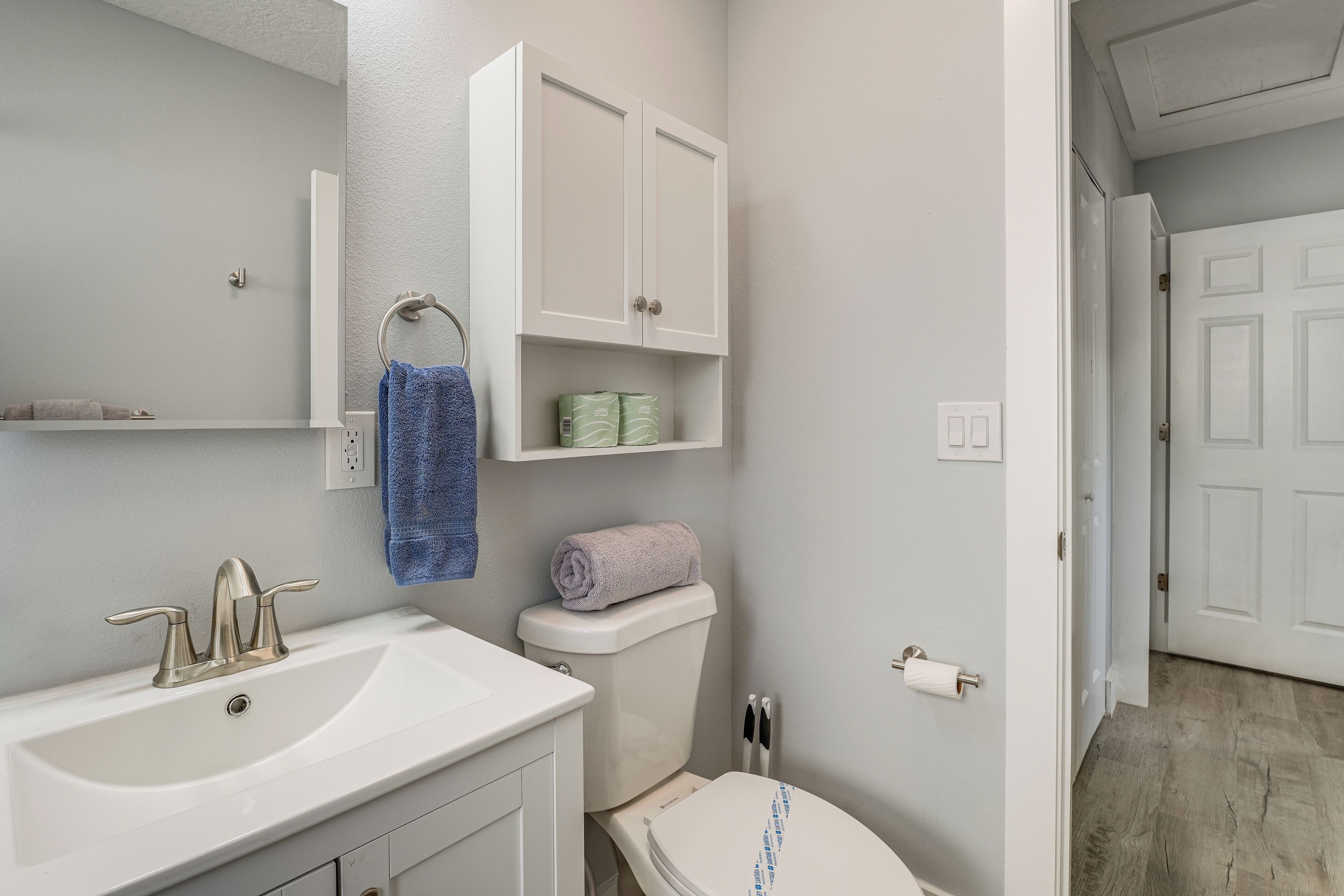 A bathroom with a white sink, a toilet, and a cabinet above the toilet.