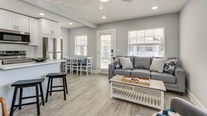A modern kitchen with white cabinets, stainless steel appliances, and a dining area with a table and chairs. - Walk to Gulf: Madeira Beach Condo w/ Patio (Madeira Beach)