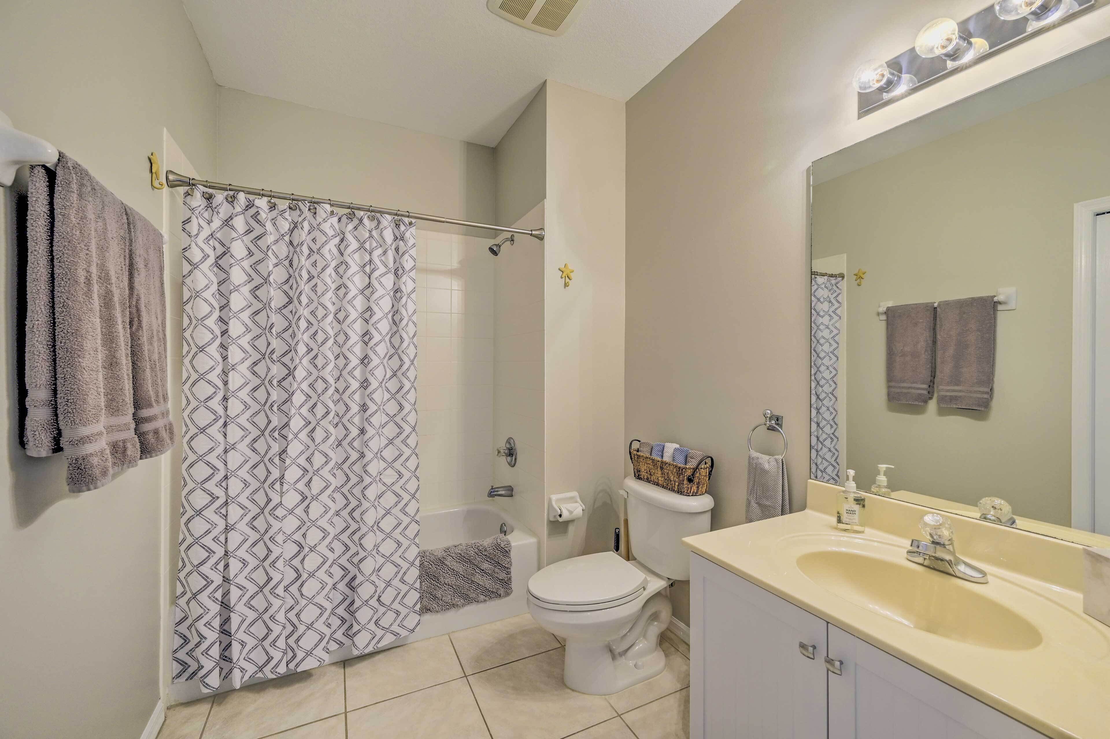 Une salle de bain équipée d’une douche, de toilettes, d’un lavabo et d’un grand miroir.