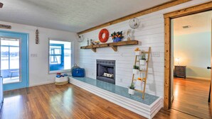 A room with wooden flooring, a fireplace, a blue door, and a window with a view.