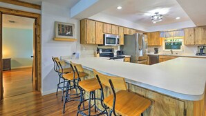A modern kitchen with wooden cabinets, a large island with bar stools, and built-in appliances.