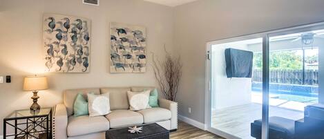 A living room with a sofa, coffee table, and artwork on the wall.
