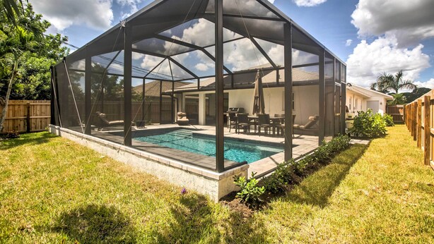 A covered outdoor area with a pool, surrounded by a wooden fence and greenery. - Naples Home w/ Lanai & Pool Near Vanderbilt Beach! (Naples)