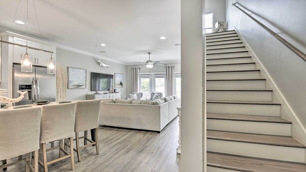 Une cuisine moderne dotée d’un îlot central, d’un coin repas avec des chaises et d’un escalier menant à l’étage supérieur.