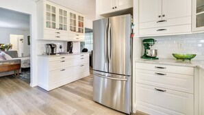 A modern kitchen with white cabinetry, a stainless steel refrigerator, and a coffee maker. - Walk to Lakes! Tropical Escape in Mount Dora (Mount Dora)
