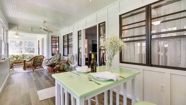 A dining area with a green table, wicker chairs, and a vase with flowers. - Walk to Lakes! Tropical Escape in Mount Dora (Mount Dora)