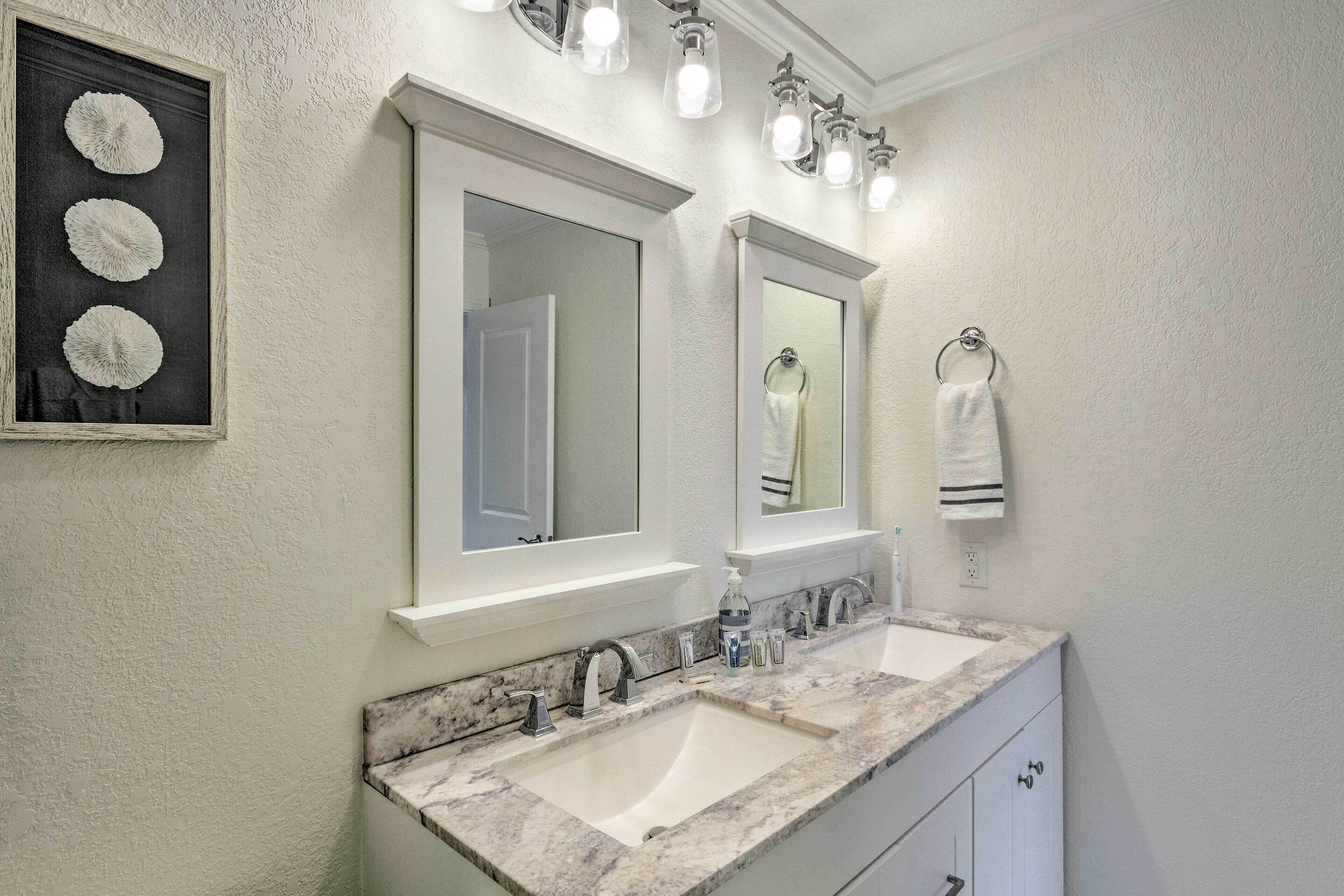 A bathroom with two sinks, a large mirror, and a framed artwork above the mirror.