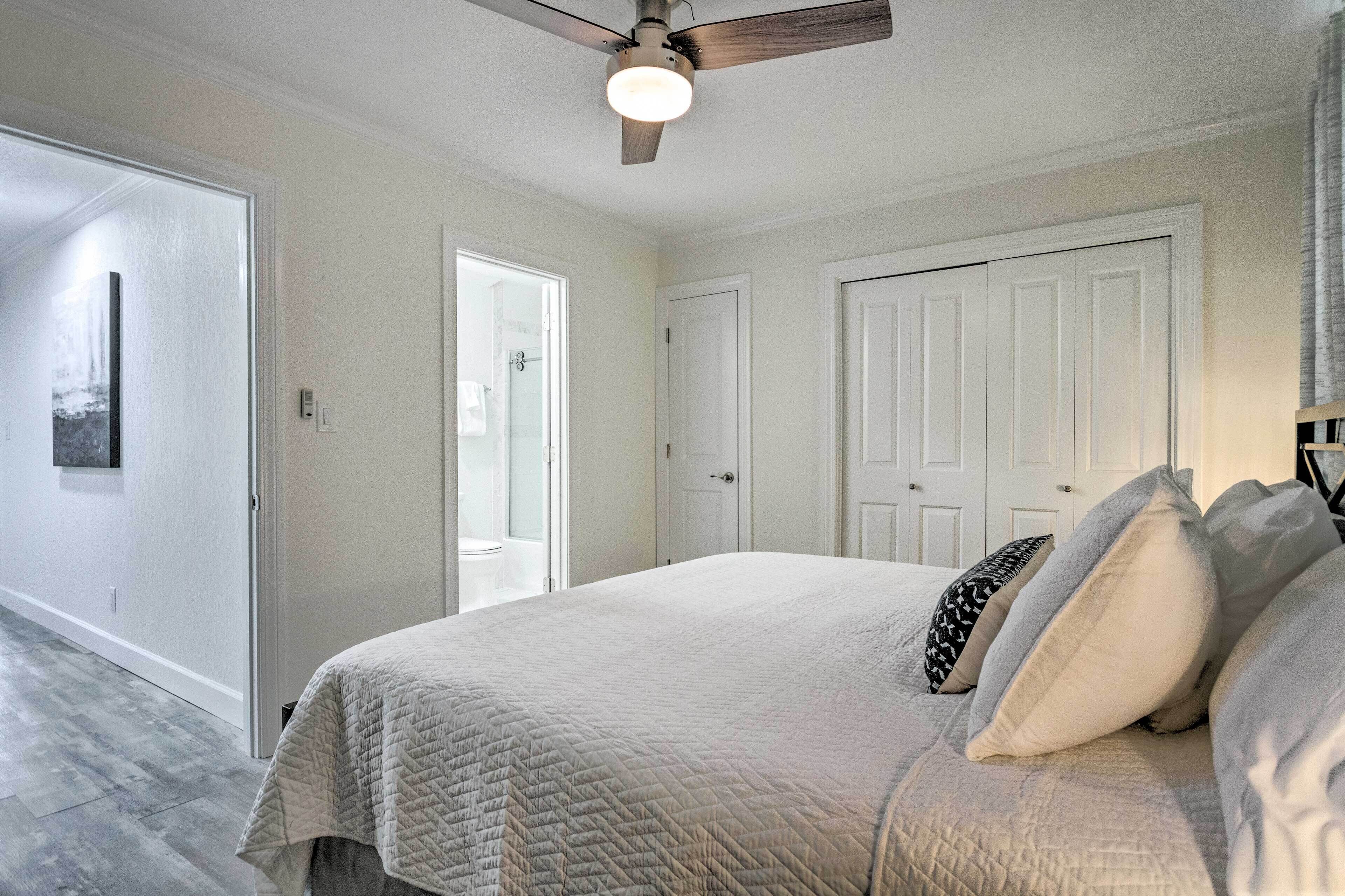 A bedroom with a bed, a ceiling fan, and a door leading to a bathroom.