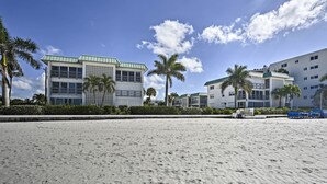 Un hôtel situé en bord de mer, composé de plusieurs bâtiments, bordé de palmiers et donnant sur une plage de sable.