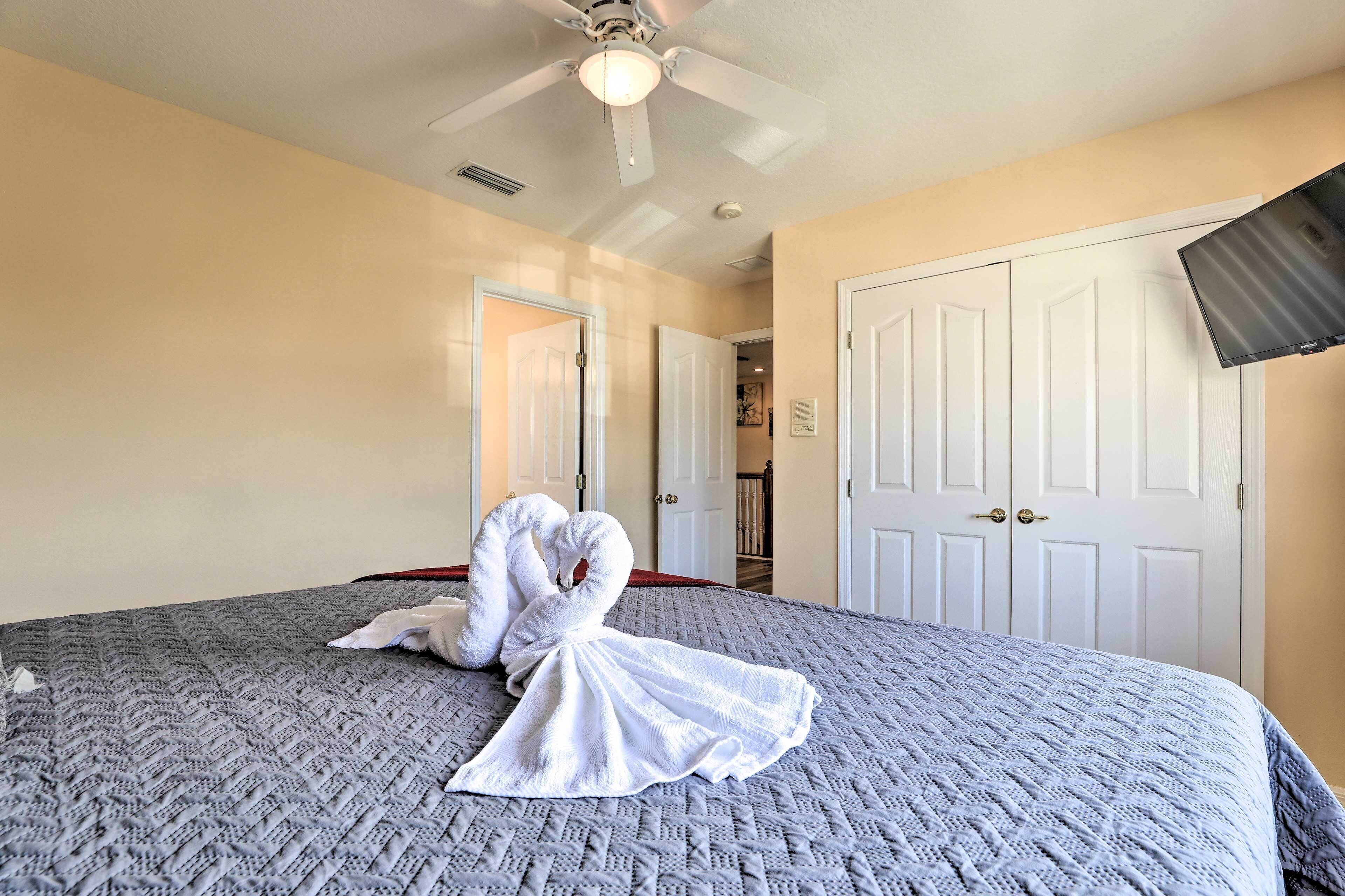 A hotel room with a large bed, a ceiling fan, and white doors.