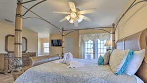 A spacious bedroom with a four-poster bed, a ceiling fan, and a large window with curtains. - 9 Mi to Parks: Disney Area Home w/ Pool & Spa! (Davenport)