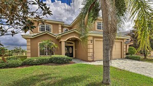 A two-story house with a beige exterior, a front entrance with a glass door, and a well-maintained lawn. - 9 Mi to Parks: Disney Area Home w/ Pool & Spa! (Davenport)