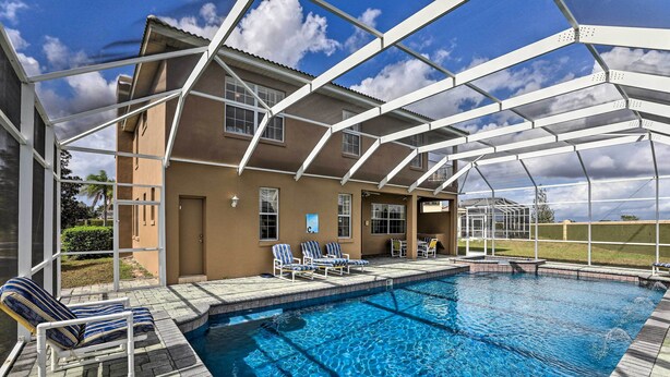 A swimming pool with a covered patio area, lounge chairs, and a view of the surrounding landscape. - 9 Mi to Parks: Disney Area Home w/ Pool & Spa! (Davenport)