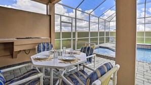 A conservatory with a pool, dining table, and chairs. - 9 Mi to Parks: Disney Area Home w/ Pool & Spa! (Davenport)