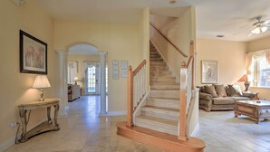 A spacious living area with a wooden staircase, a sofa set, and a console table with a lamp. - 9 Mi to Parks: Disney Area Home w/ Pool & Spa! (Davenport)