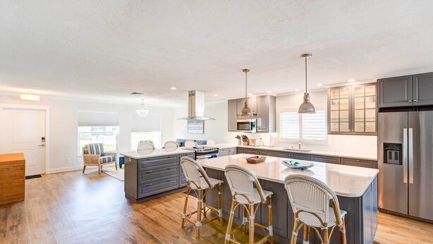 A modern kitchen with a central island, bar stools, and stainless steel appliances.