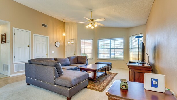 A living room with a gray sectional sofa, a wooden coffee table, and a laptop on a desk. - Navarre Vacation Rental Home ~ 4 Mi to Beach! (Navarre)