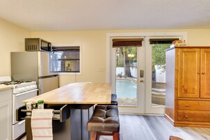 A kitchen with a wooden table, a built-in oven, and a refrigerator.